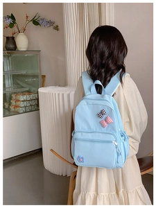 Detail of light blue school backpack with cute plaid bows and flower on the back pocket