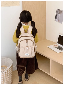 Close-up of children's beige backpack with drawstring pocket and adjustable straps