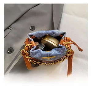 Détail du sac seau en denim bleu montrant l'espace pour rouge à lèvres et cosmétiques