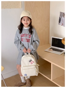 Lifestyle view of a large capacity cream schoolbag with bows and floral details