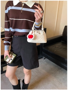 Detailansicht einer weißen gepunkteten Muscheltasche mit Kirsch-Anhänger und Metallteilen