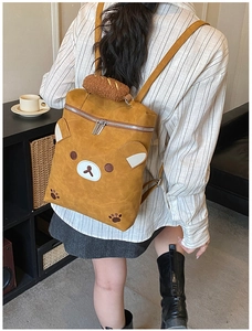 Detail view of the yellow bear backpack showing its plush handle and leather texture