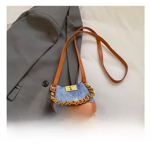 Détail du mini sac seau en denim et cuir avec chaîne dorée et surpiqûres en losange