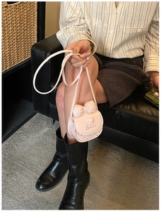Détail du mini sac bandoulière rose avec nœud papillon et motif animal sur tenue rayée