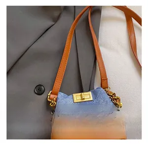 Vue détaillée d'un mini sac seau en denim bleu et cuir marron avec fermoir doré brillant