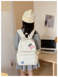 Detailed close-up of white school backpack with cute bow and floral patches decoration