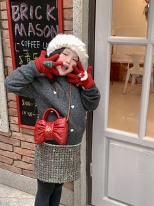 Detail of red bow-shaped crossbody bag with gold chain for children Christmas outfit