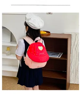 Rear view of a child wearing the red and pink fruit-themed backpack in a home setting