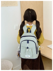 Detail of sage green nylon backpack featuring navy contrast trim and drawstring pocket