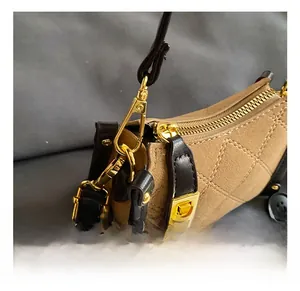 Macro shot of gold metal hooks and black leather strap on a quilted khaki handbag