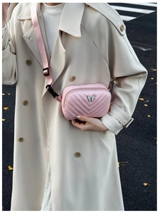 Close-up of pink quilted crossbody bag for kids with silver butterfly logo and adjustable strap