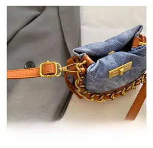 Détail du mini sac seau en denim bleu clair avec crochets dorés et finitions en cuir