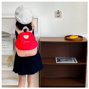 Detailed back view of a red and pink kids backpack with cute heart and star patterns