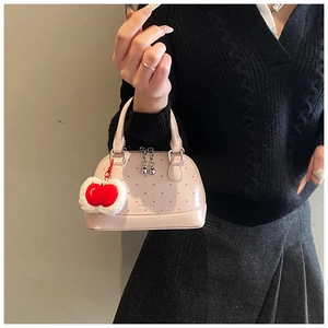 Gros plan d'un sac coquille rose à pois avec pendentif pomme et fermeture éclair en métal