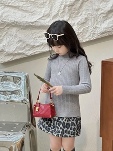 Asiatisches Mädchen-Model trägt grauen Strickpullover und rote gesteppte Minitasche