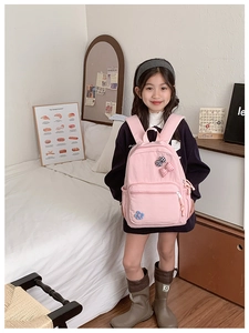 Detail of pink school backpack for girls featuring plaid bows and embroidered flower motifs