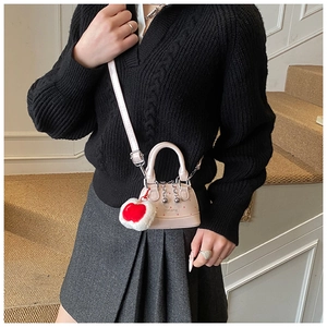 Pink mini shell crossbody bag with heart pendant and metallic chain on a model