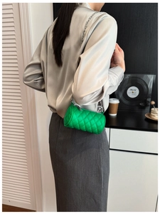 Detail view of green quilted cylinder shoulder bag for children with silver chain strap