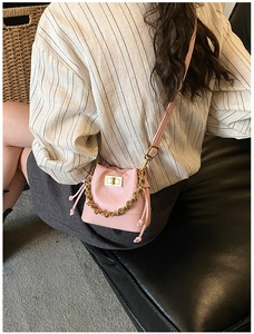 Détail du mini sac seau matelassé rose avec chaîne dorée porté par un mannequin