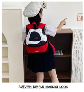 Kid's fruit-themed red and black backpack shown on a model in a library setting