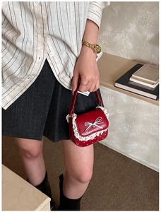 Detail of red Lolita style mini bag with white lace trim, bow, and polka dots pattern