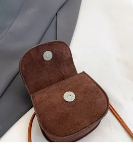 Close-up of the silver magnetic snap fastener on a brown matte cute cartoon kids crossbody bag