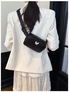 Detail of black PU leather kids chest bag with V-quilted pattern and white butterfly buckle