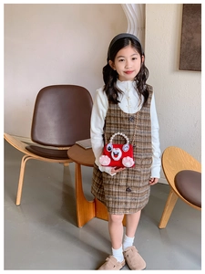 Detail of red plush kitten purse with pearl handle on a girl's plaid pinafore dress