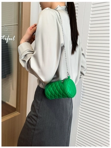 Detail view of bright green quilted mini cylinder bag with silver chain strap on model