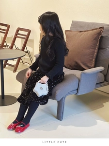 Girl in chic black knitwear and sequin skirt holding a silver star pearl handbag
