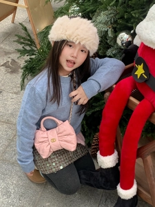 Detailed view of pink bow-shaped quilted handbag with golden chain strap for kids