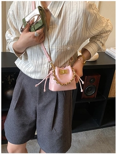 Détail du mini sac seau rose à cordon avec poignée chaîne dorée et fini matelassé