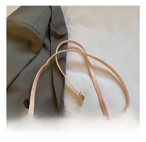 Gros plan détaillé d'un sac bandoulière rose avec broderie cœur et sangle ajustable