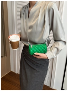 Detail view of the green quilted cylinder mini bag with silver chain strap on model