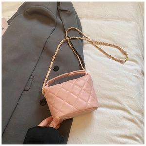 Détail du sac bandoulière matelassé rose avec chaîne dorée sur vêtement élégant
