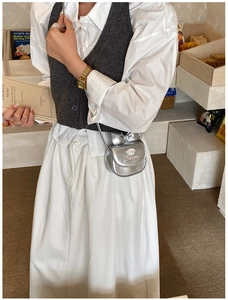 Mini sac bandoulière argenté avec nœud et broderie dans un décor de café chic