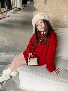 Close-up of a red knit dress styled with a beige quilted handbag in a modern setting