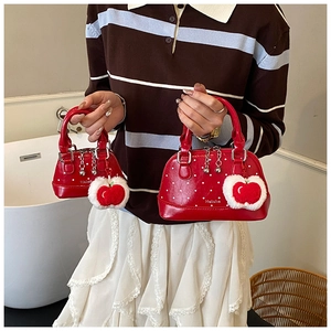 Détail de sacs coquillages à pois rouges avec pendentif pomme et logo Helahe