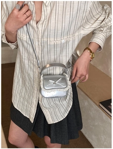 Close-up of a silver bow handbag with lace trim and adjustable shoulder strap for kids