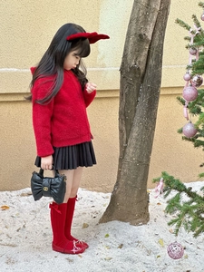 Detail of a child black quilted chain handbag with bow and festive holiday outfit accessories