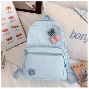 Detail of light blue school bag with plaid bow appliques and floral embroidery