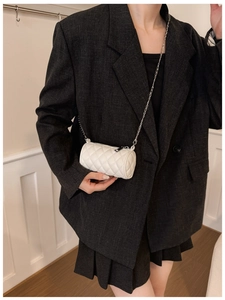 Detail of white quilted cylindrical crossbody bag with silver chain strap on model