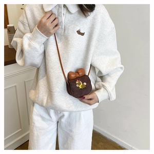 Detail of dark brown suede mini crossbody bag with leather bow and puppy embroidery