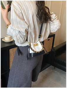 Vue lifestyle d'un sac seau matelassé noir et blanc avec chaîne porté par un mannequin