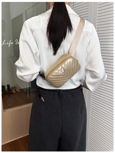 Detail of golden mini chest bag with V-shaped stitching and white butterfly logo