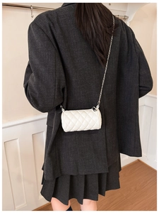 Detailed view of white quilted cylinder mini bag with silver chain strap on model