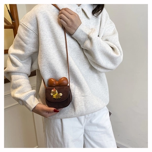 Detail of cute brown mini crossbody bag with leather bow and cartoon animal embroidery
