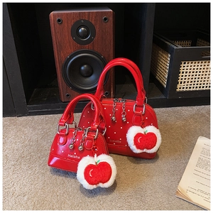 Detail of red polka dot shell bags with apple charms and dual metal beaded zippers