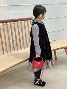 Détail d'un sac à bandoulière matelassé rouge avec chaîne dorée tenu par un enfant