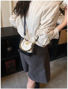 Détail du mini sac seau bicolore avec motif matelassé et chaîne dorée décorative